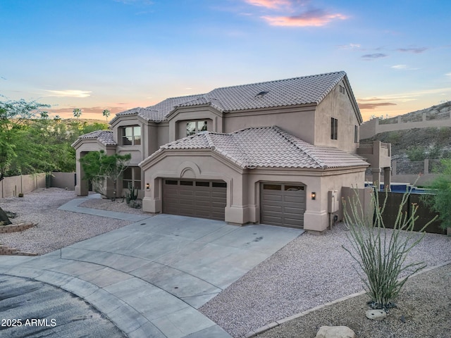 view of front facade featuring an attached garage, stucco siding, a tile roof, fence, and concrete driveway