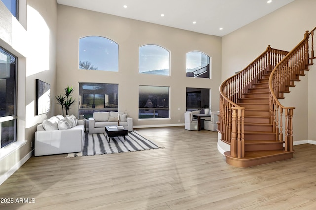 living area with stairway, a high ceiling, and wood finished floors