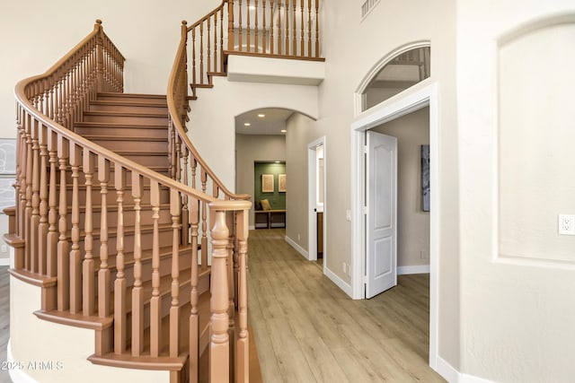 entrance foyer with stairs, visible vents, light wood finished floors, arched walkways, and baseboards