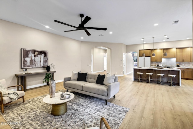 living room featuring visible vents, recessed lighting, light wood-style flooring, arched walkways, and a ceiling fan