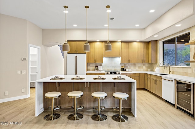 kitchen with high end fridge, light wood finished floors, white dishwasher, beverage cooler, and a kitchen island