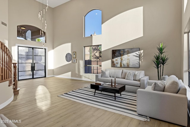 living area featuring stairway, wood finished floors, baseboards, and a high ceiling