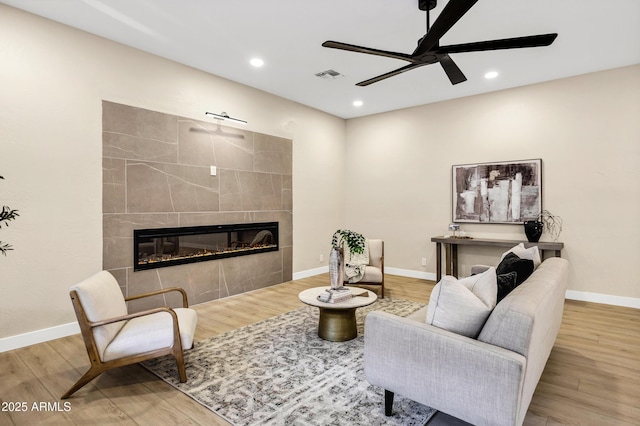 living room featuring a fireplace, ceiling fan, visible vents, and wood finished floors