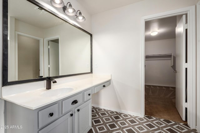 6637 W Watkins St, Phoenix, AZ 85043 - bathroom featuring vanity, a walk in closet, tile patterned floors, and baseboards