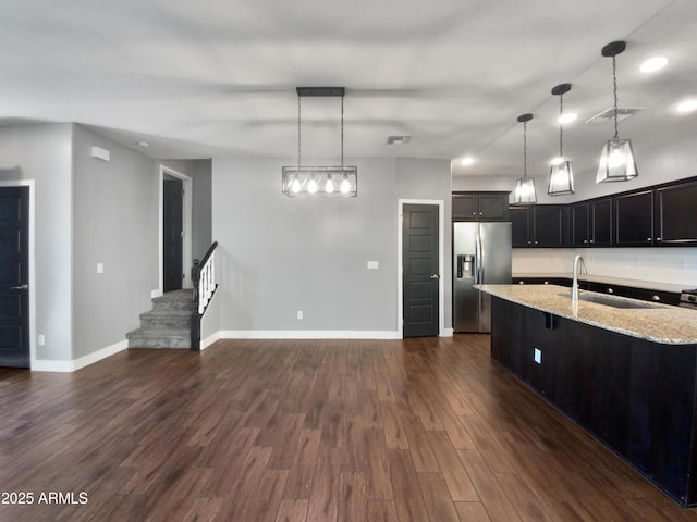 kitchen featuring sink, a kitchen island with sink, pendant lighting, and stainless steel fridge with ice dispenser