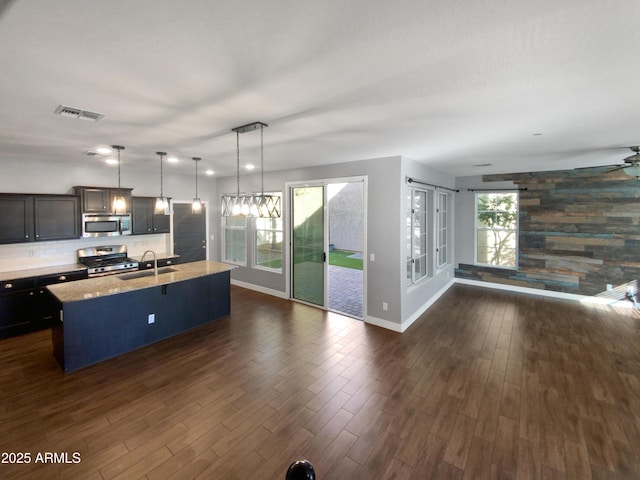 kitchen featuring decorative light fixtures, plenty of natural light, appliances with stainless steel finishes, and a center island with sink