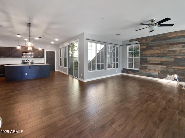 unfurnished living room featuring ceiling fan and wooden walls