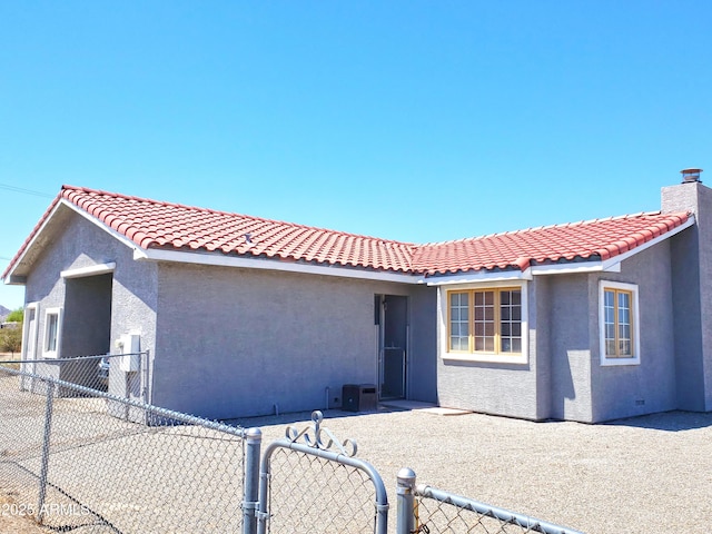 69762 Old Bell Rd, Salome, AZ 85348 - view of front of house featuring stucco siding, a gate, a tiled roof, and a chimney