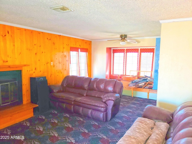 69762 Old Bell Rd, Salome, AZ 85348 - carpeted living area with crown molding, a textured ceiling, wood walls, a ceiling fan, and a glass covered fireplace