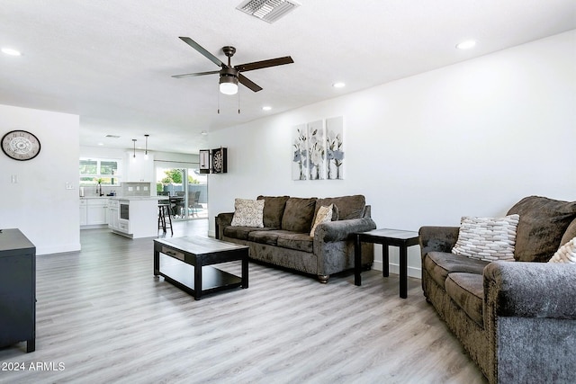 living room featuring ceiling fan, light hardwood / wood-style floors, and sink