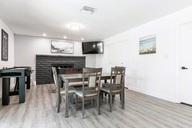 dining space featuring a fireplace and light hardwood / wood-style flooring