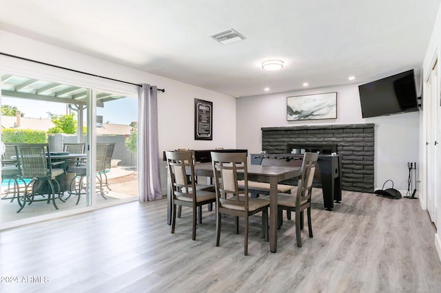 dining area featuring a brick fireplace and light wood-type flooring