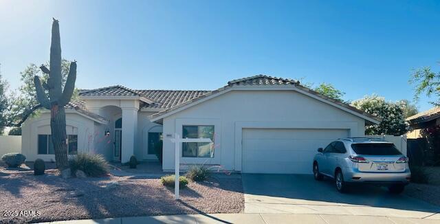 view of front of house featuring a garage, driveway, and a tiled roof