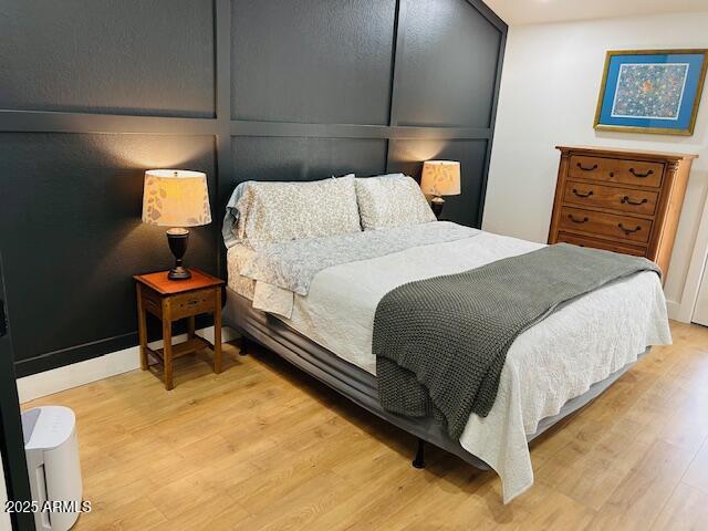 bedroom featuring light wood finished floors and a decorative wall