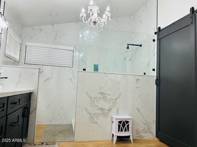 bathroom with a marble finish shower, a chandelier, and vanity