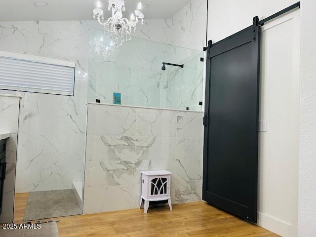 bathroom featuring a marble finish shower, wood finished floors, and a chandelier