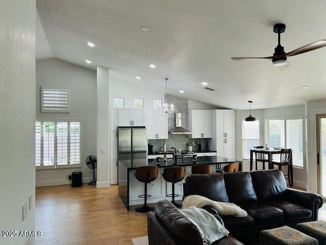 living room featuring wood finished floors, a ceiling fan, recessed lighting, a chandelier, and high vaulted ceiling