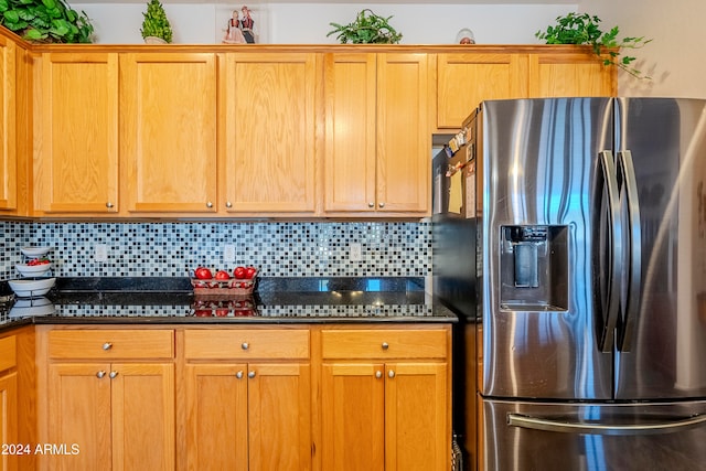 kitchen featuring backsplash, dark stone countertops, and stainless steel fridge with ice dispenser