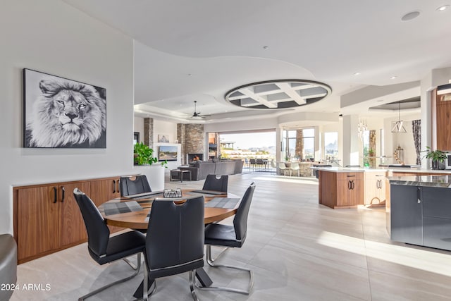 tiled dining space with ceiling fan and a large fireplace