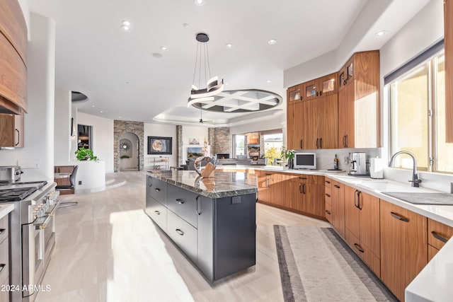 kitchen with pendant lighting, a center island, sink, double oven range, and dark stone countertops