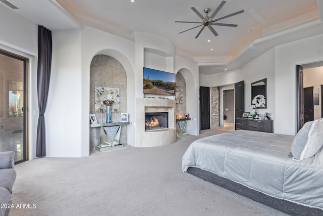 carpeted bedroom with a high end fireplace and ceiling fan