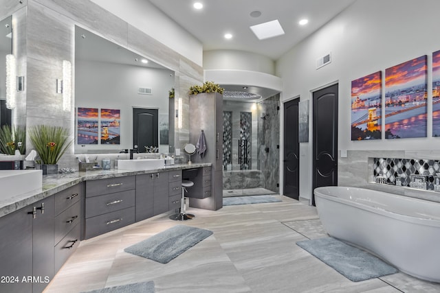 bathroom with vanity, separate shower and tub, and a towering ceiling