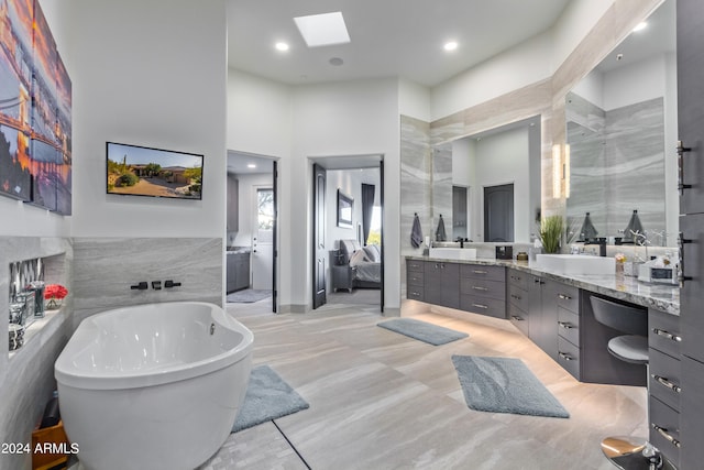 bathroom with vanity, tile walls, and a tub