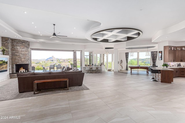 interior space with a healthy amount of sunlight, ceiling fan, billiards, and a stone fireplace