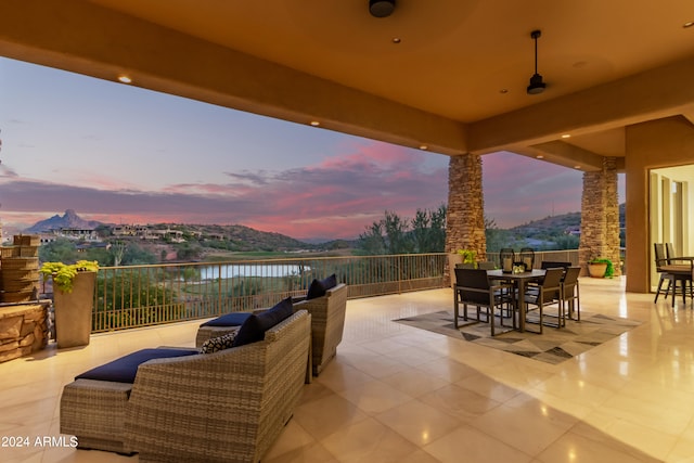 patio terrace at dusk with a balcony, a water view, and an outdoor living space