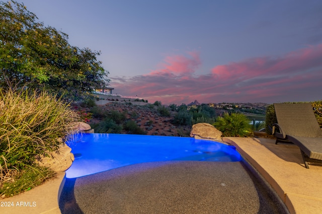 pool at dusk featuring a patio area