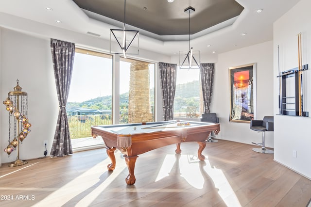 rec room with light wood-type flooring, pool table, a wealth of natural light, and a raised ceiling