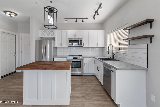 kitchen featuring a kitchen island, stainless steel appliances, sink, white cabinetry, and decorative light fixtures