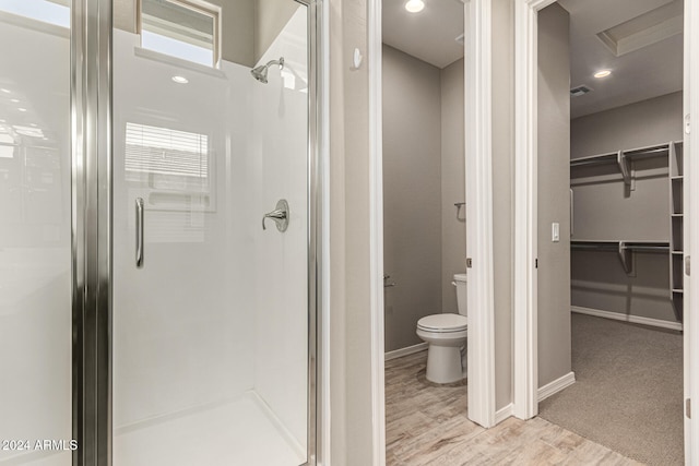 bathroom with wood-type flooring, toilet, and an enclosed shower