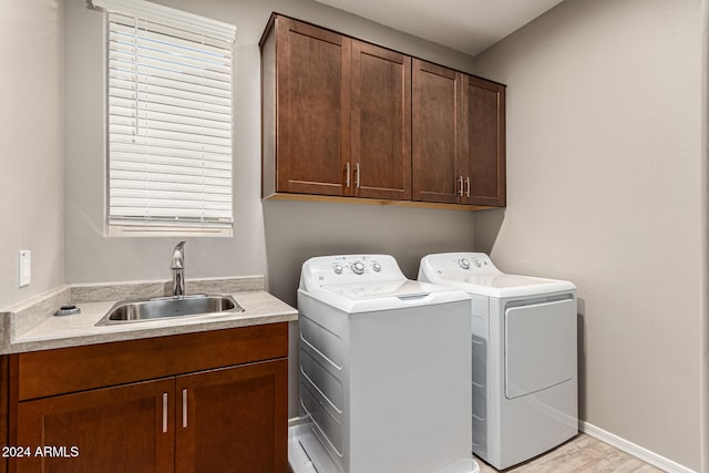 clothes washing area with washing machine and clothes dryer, sink, and cabinets