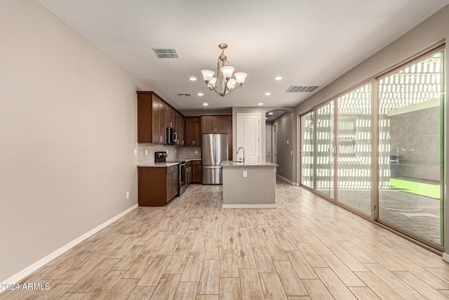 kitchen featuring a center island with sink, plenty of natural light, stainless steel appliances, and light hardwood / wood-style floors