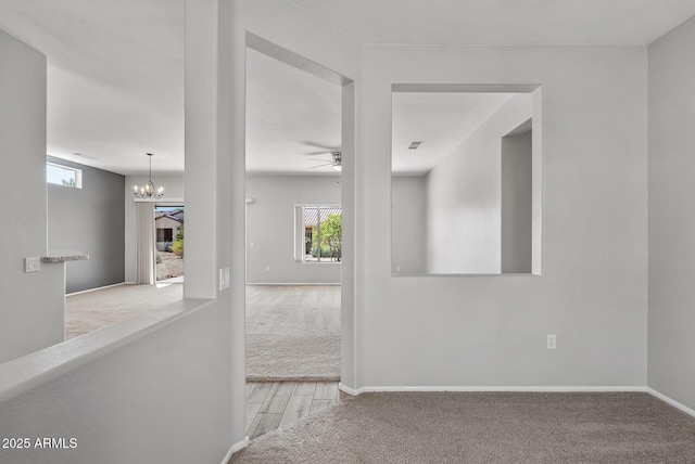 hall with light colored carpet and a notable chandelier