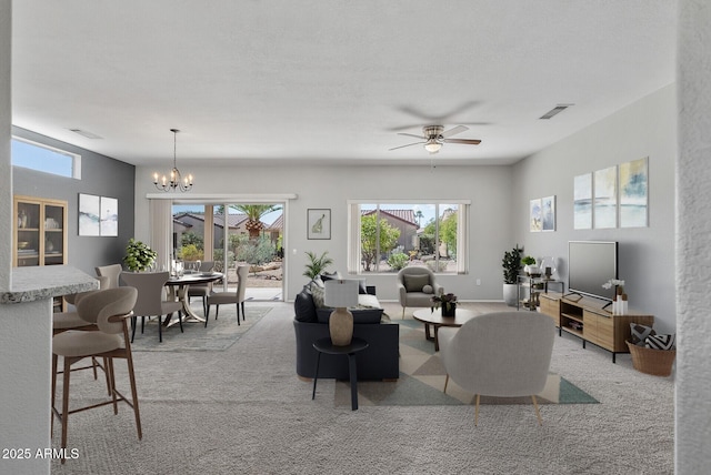 living room with light colored carpet, a wealth of natural light, and ceiling fan with notable chandelier