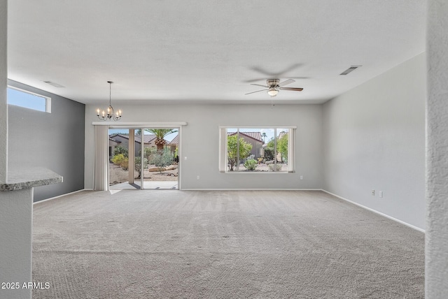 unfurnished room with carpet floors, ceiling fan with notable chandelier, and a healthy amount of sunlight