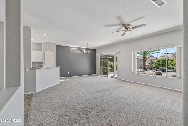 unfurnished living room featuring ceiling fan with notable chandelier, sink, and light carpet