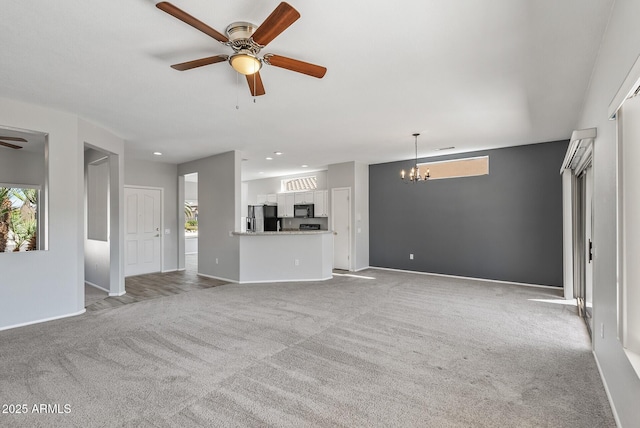 unfurnished living room featuring light carpet, a healthy amount of sunlight, and ceiling fan with notable chandelier