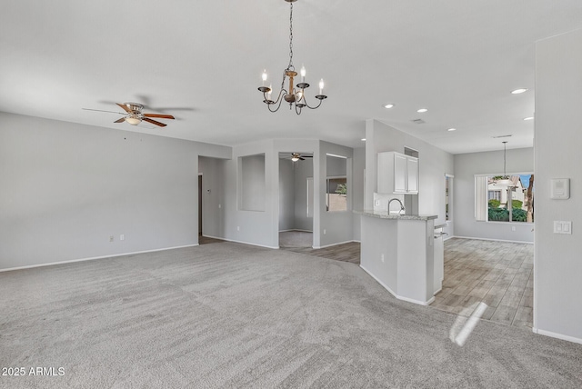 unfurnished living room featuring ceiling fan, light carpet, and sink