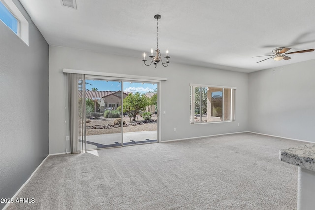 carpeted spare room featuring ceiling fan with notable chandelier