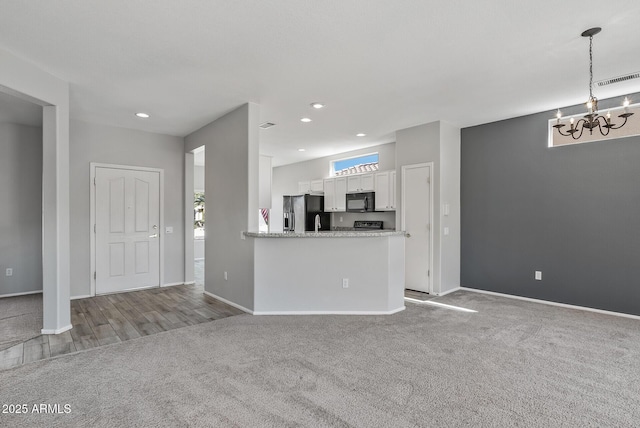 unfurnished living room featuring light colored carpet and an inviting chandelier