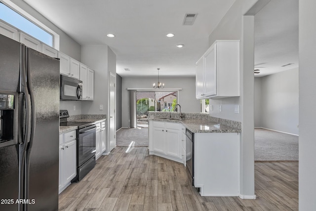 kitchen featuring kitchen peninsula, pendant lighting, white cabinets, and black appliances