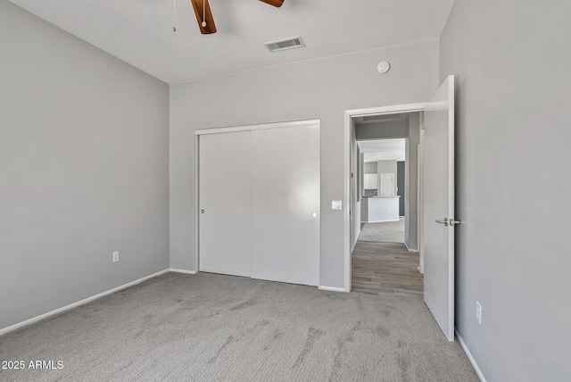 unfurnished bedroom featuring ceiling fan, light colored carpet, and a closet