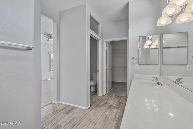 bathroom with toilet, ceiling fan, and vanity