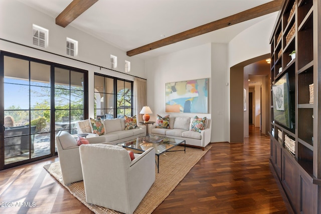 living area with beam ceiling, visible vents, arched walkways, and wood finished floors