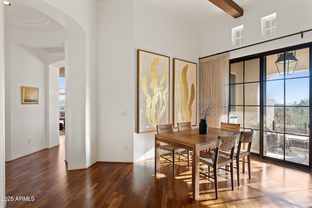 dining room featuring arched walkways, visible vents, beamed ceiling, and wood finished floors