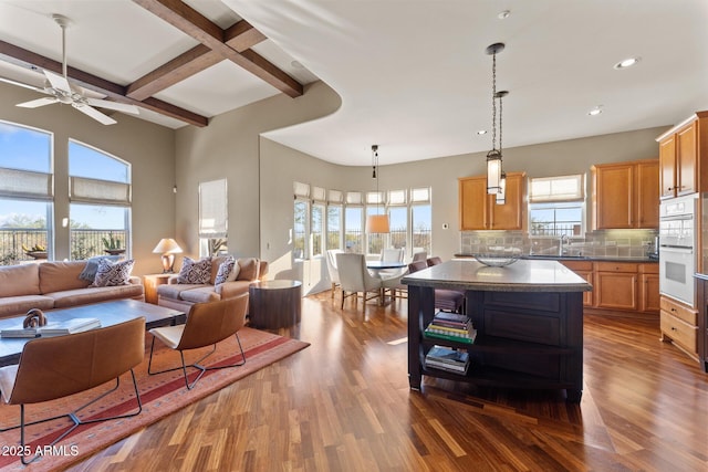 kitchen featuring tasteful backsplash, dark countertops, open floor plan, dark wood-style flooring, and beam ceiling