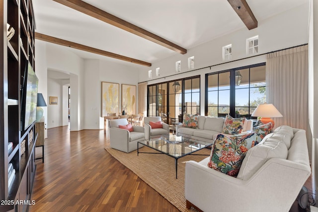 living area with arched walkways, a fireplace, wood finished floors, and beam ceiling